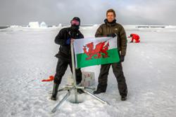 Two Bangor researchers place a core through the sea ice- and decorate it with the Red Dragon!