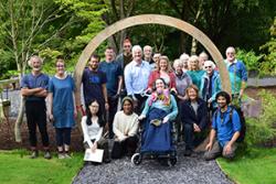 Dr Sophie Williams (in wheelchair) and well-wishers at the ribbon-cutting ceremony for the Moongate entrance to the new Chinese Garden at Treborth, near ŷ԰Ƭ.