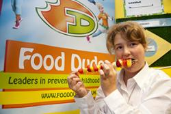 A pupil enjoys a fruit kebab.