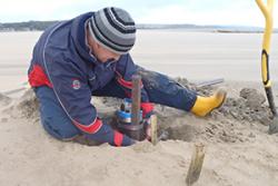 Placing a pressure sensor to measure wave heights across the foreshore in front of the salt marsh at Red Wharf Bay, Ynys Môn.