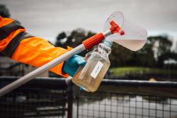 A member of staff collects waste water for monitoring.